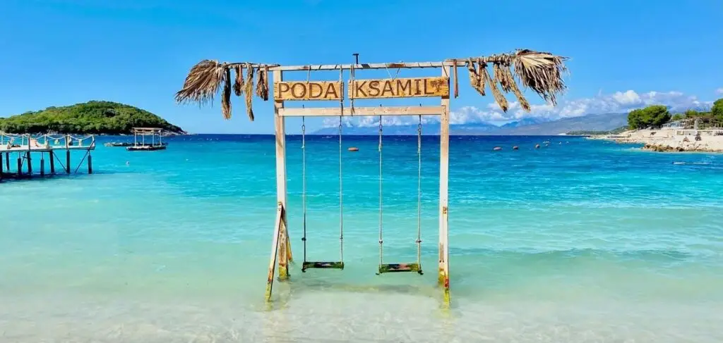 Plage de Ksamil avec des eaux turquoises et une balançoire en bois dans l'eau, suggérant un cadre idyllique pour la plongée à Saranda et Ksamil en Albanie