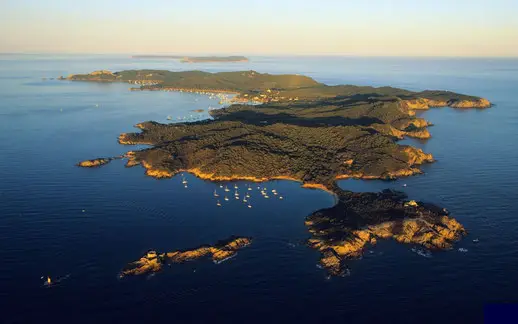 Vue aérienne de l'île de Porquerolles entourée d'eaux bleues et de bateaux au mouillage, un site prisé pour la plongée sous-marine en Méditerranée.