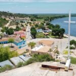 Vue aérienne d'une ville près de Benguela avec une grande croix blanche, une église et une rivière longeant le paysage verdoyant en Angola