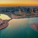Vue aérienne de la corniche de Dammam avec la tour emblématique au coucher du soleil, en bord de mer d’Arabie