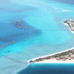 Vue aérienne d’une île au large d’Al Wajh en mer Rouge, avec villas sur pilotis et eaux turquoise, destination prisée pour la plongée
