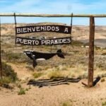 Panneau d’entrée de Puerto Pirámides avec vue sur la baie de plongée