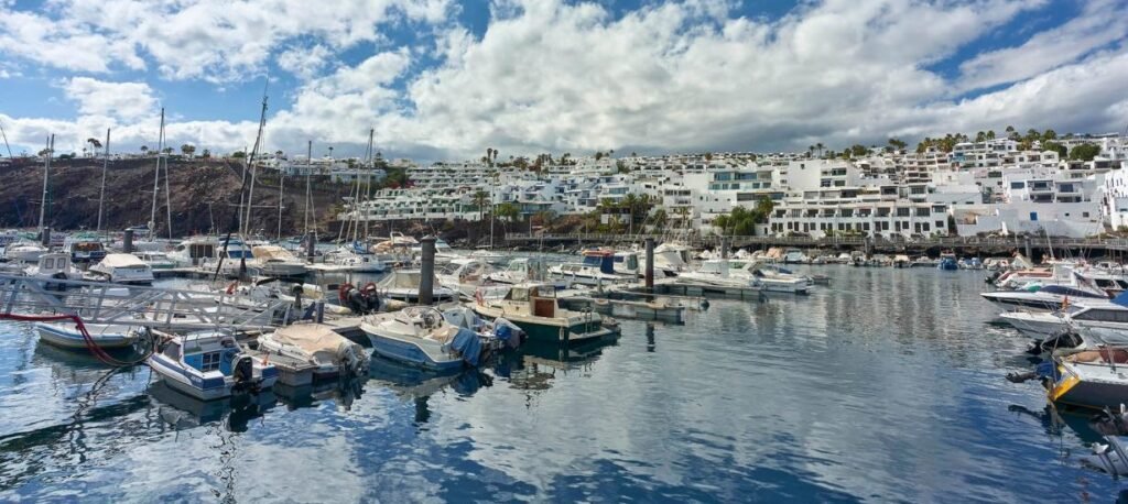 Port de plaisance de Puerto del Carmen avec les bateaux et les maisons blanches sur la colline