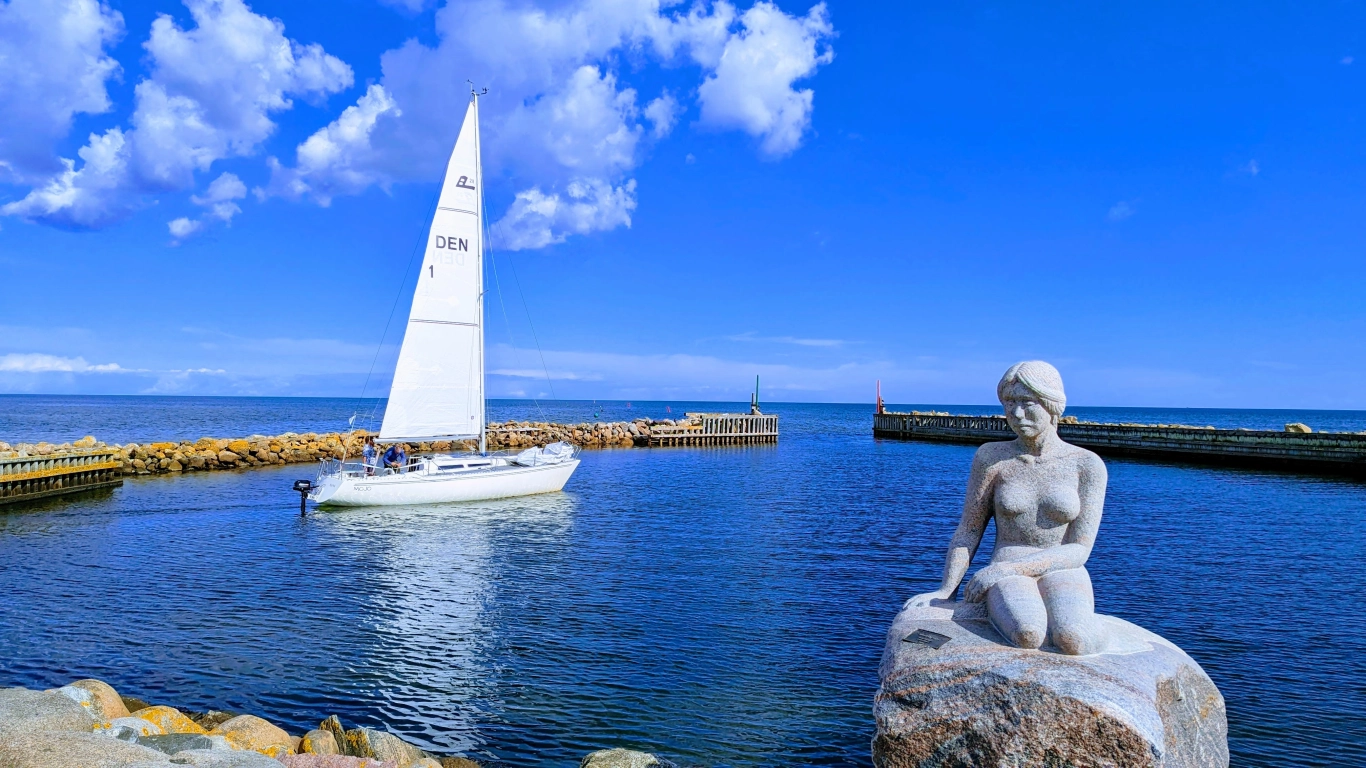 Voilier entrant dans le port d Asaa au Danemark avec une statue en pierre au premier plan et la mer du Kattegat en arrière plan