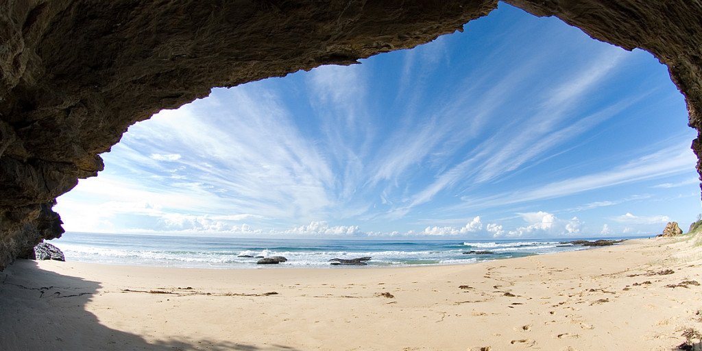 Plage isolée près de Karachi vue depuis une cavité rocheuse avec l’océan et un ciel bleu